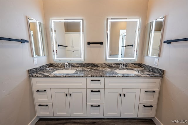 bathroom featuring double vanity, baseboards, and a sink