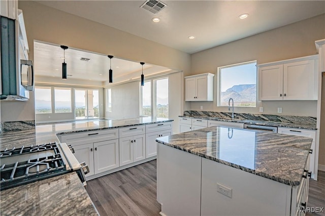 kitchen featuring gas range oven, white cabinetry, and light stone countertops