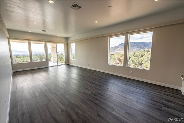 empty room featuring a mountain view, recessed lighting, visible vents, baseboards, and dark wood finished floors