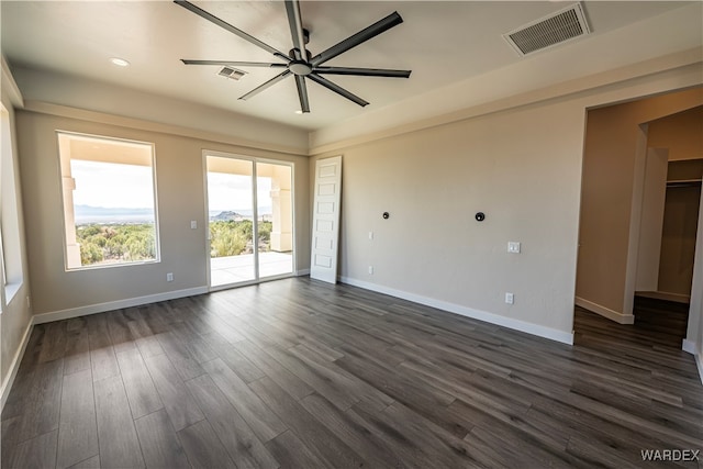 empty room featuring dark wood-type flooring, visible vents, ceiling fan, and baseboards