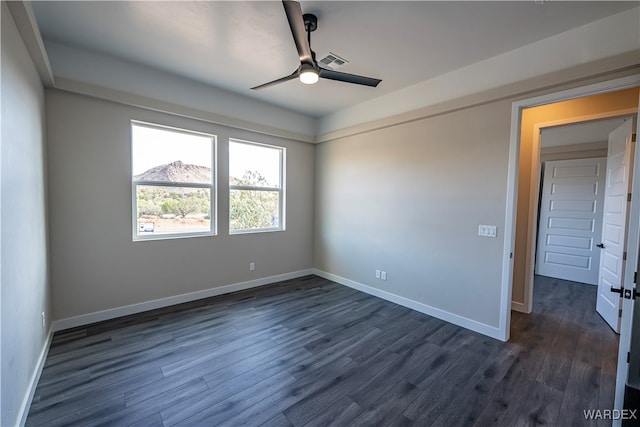 empty room featuring dark wood-type flooring, visible vents, ceiling fan, and baseboards