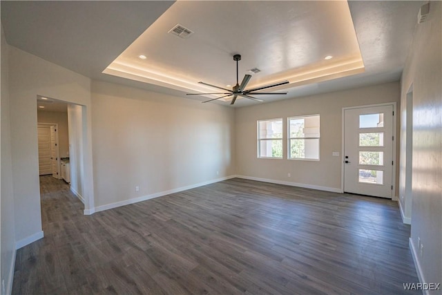 interior space featuring a raised ceiling, visible vents, baseboards, and dark wood-style flooring