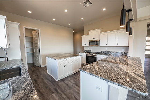 kitchen featuring stainless steel appliances, dark stone countertops, a sink, and white cabinetry