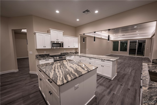 kitchen featuring white cabinets, light stone counters, stainless steel appliances, and a center island