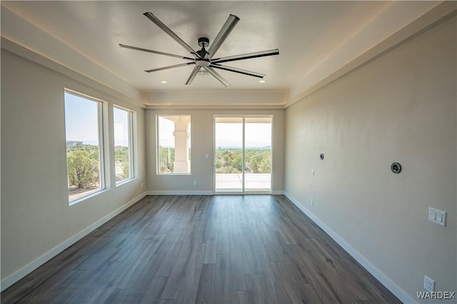 spare room with ceiling fan, baseboards, and dark wood-type flooring