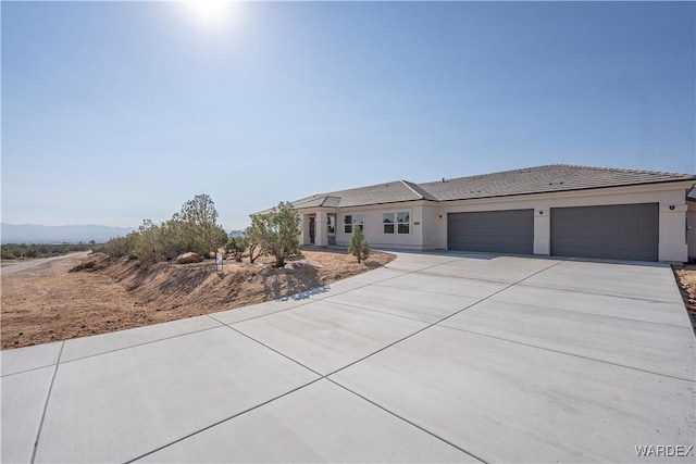 view of front of home featuring stucco siding, concrete driveway, an attached garage, a mountain view, and a tiled roof