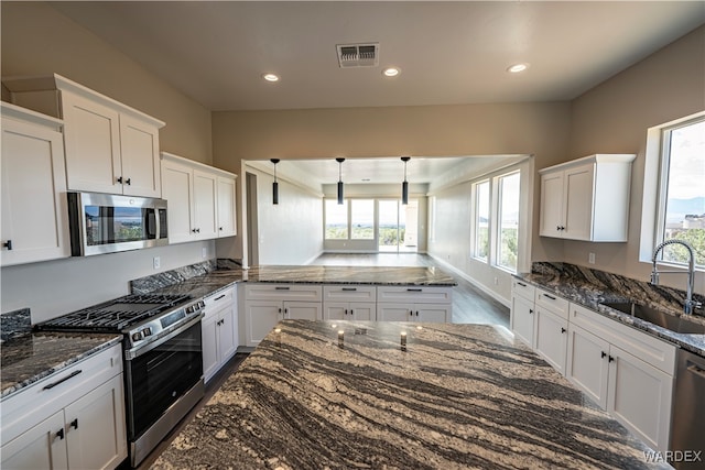 kitchen featuring visible vents, white cabinets, stainless steel appliances, pendant lighting, and a sink