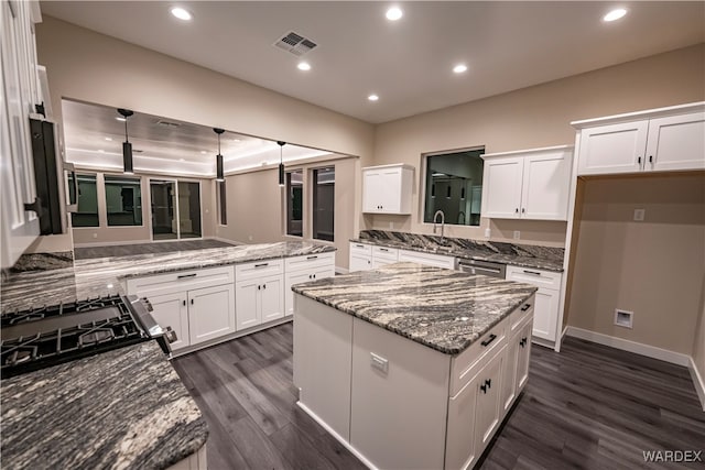 kitchen featuring light stone counters, dark wood-style flooring, a center island, and white cabinets