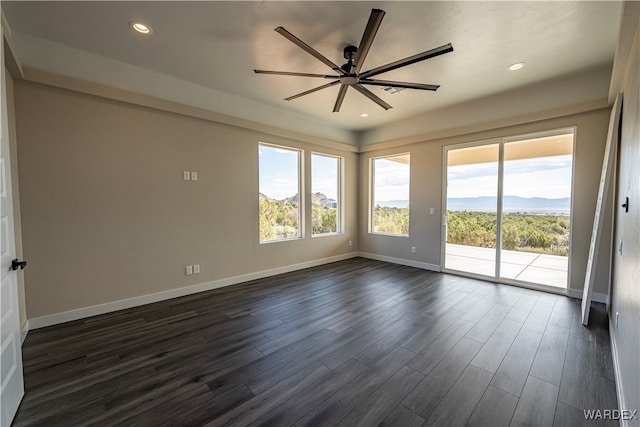 spare room with a mountain view, recessed lighting, dark wood-type flooring, a ceiling fan, and baseboards