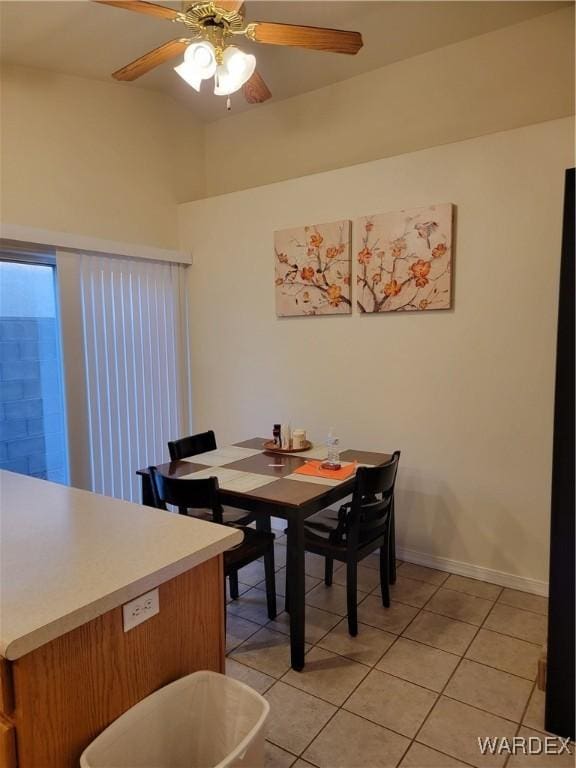 dining space featuring baseboards, a ceiling fan, and light tile patterned flooring