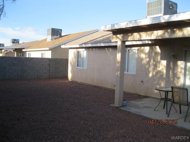 exterior space with fence, central AC unit, a patio area, and stucco siding