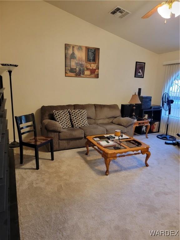 living area featuring carpet floors, visible vents, and lofted ceiling