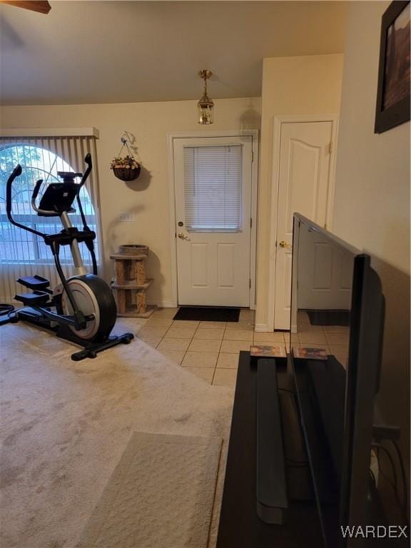 exercise room with light colored carpet, baseboards, and light tile patterned floors