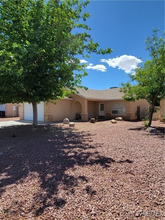 ranch-style house featuring an attached garage, stucco siding, and fence