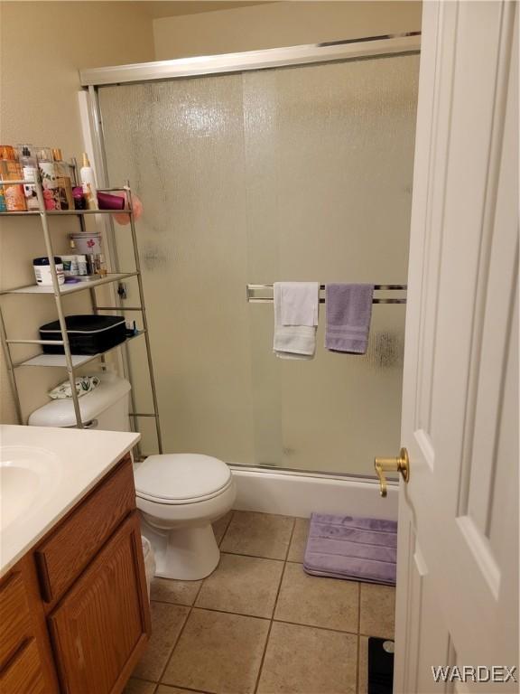 bathroom with vanity, tile patterned flooring, a stall shower, and toilet