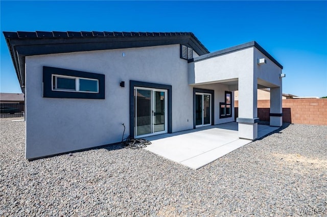 rear view of house with a patio area, fence, and stucco siding