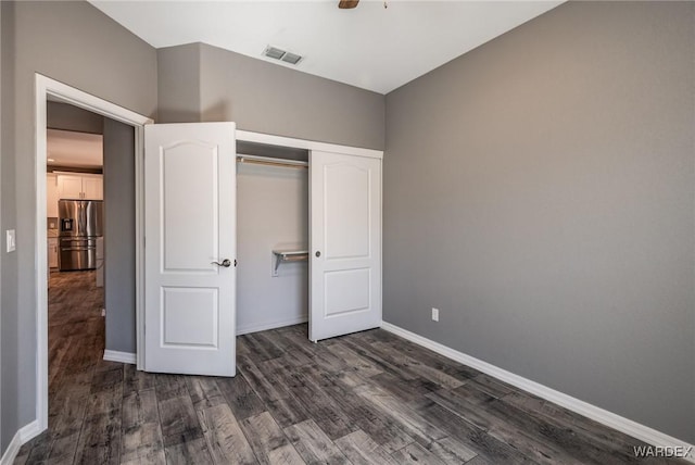 unfurnished bedroom with baseboards, visible vents, stainless steel fridge with ice dispenser, dark wood-style floors, and a closet