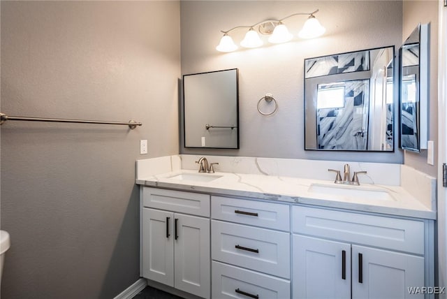 bathroom featuring double vanity, baseboards, and a sink