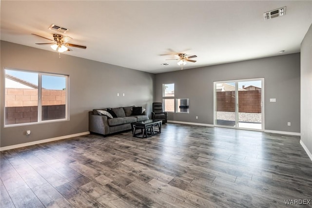 living room with dark wood-style flooring, visible vents, and a healthy amount of sunlight