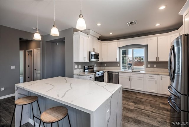 kitchen featuring stainless steel appliances, white cabinets, and hanging light fixtures