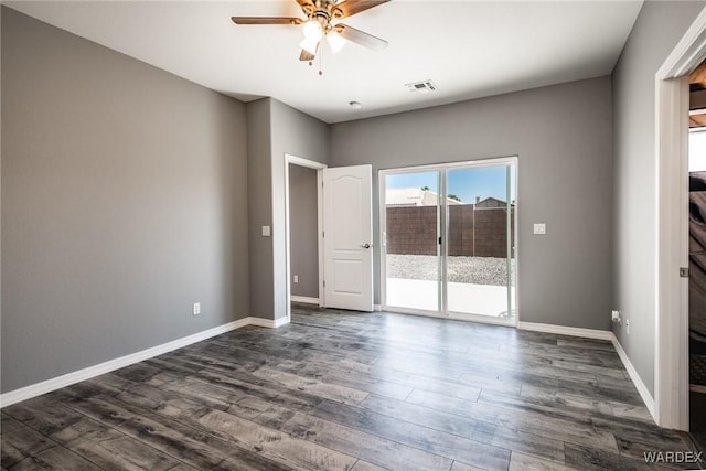 unfurnished room with dark wood-style floors, visible vents, a ceiling fan, and baseboards