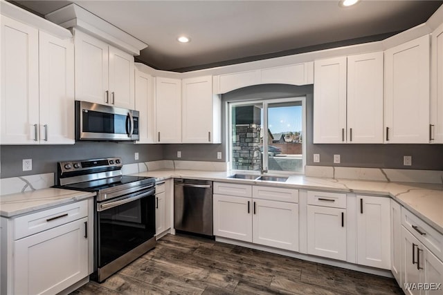 kitchen featuring appliances with stainless steel finishes, white cabinets, and a sink