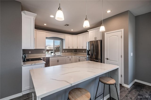 kitchen with appliances with stainless steel finishes, a center island, white cabinets, and hanging light fixtures