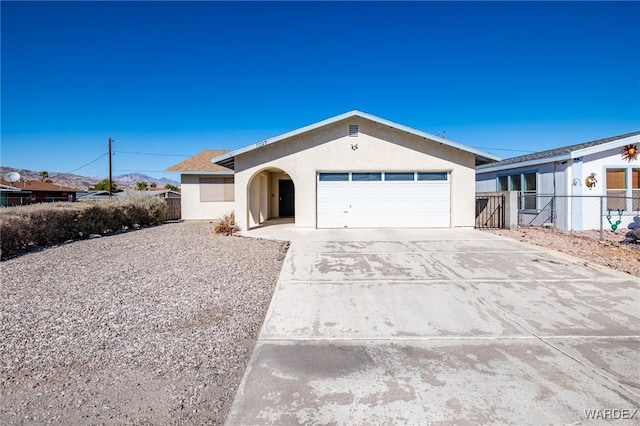 ranch-style home featuring a garage, driveway, fence, and stucco siding