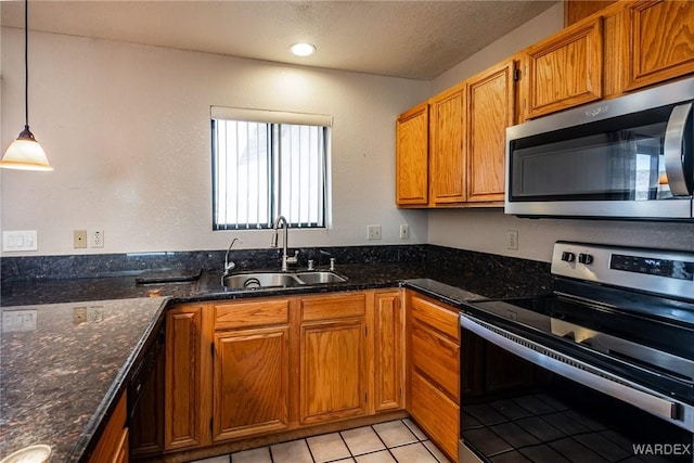 kitchen with hanging light fixtures, dark stone countertops, appliances with stainless steel finishes, and a sink