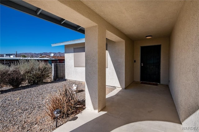 view of exterior entry featuring fence, a patio, and stucco siding