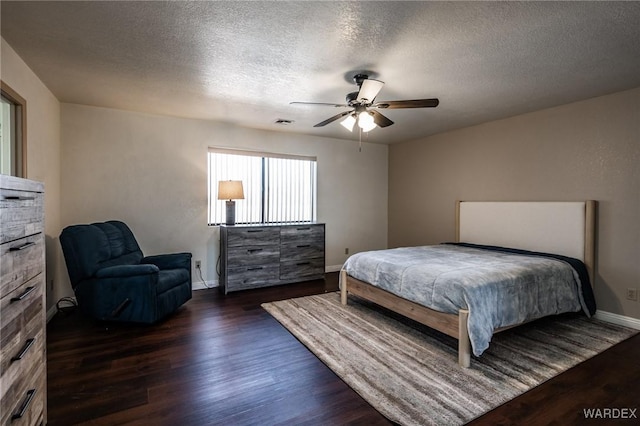 bedroom featuring ceiling fan, a textured ceiling, visible vents, baseboards, and dark wood-style floors