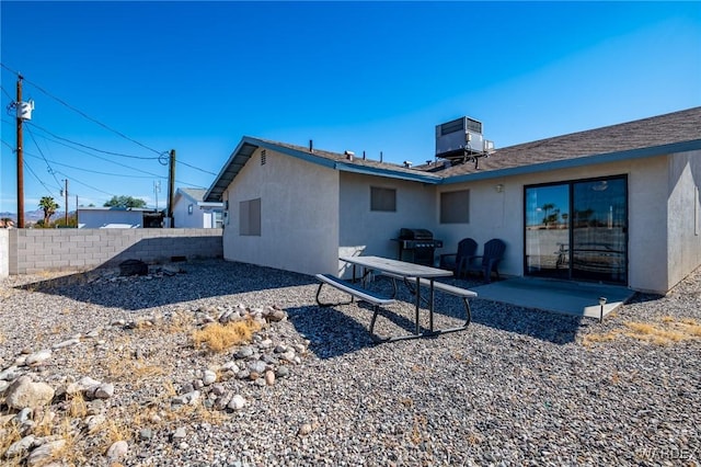 rear view of property featuring central AC, fence, a patio, and stucco siding