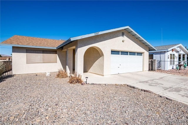 ranch-style house with driveway, an attached garage, fence, and stucco siding