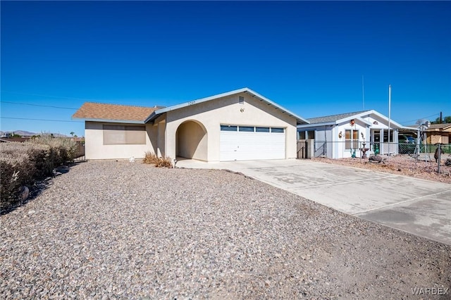 ranch-style home featuring concrete driveway, an attached garage, fence, and stucco siding