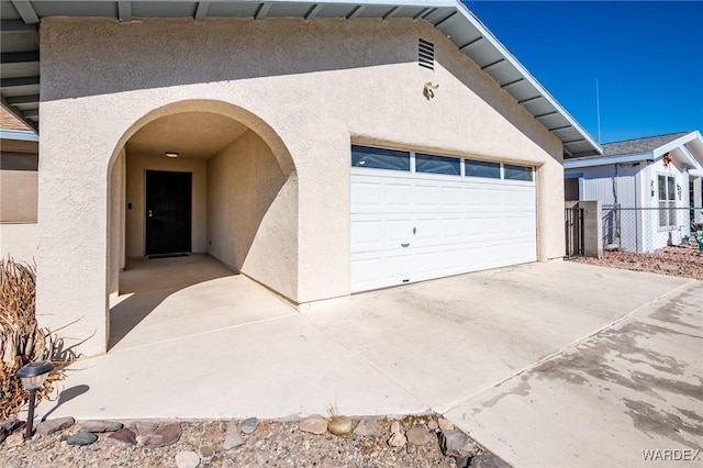 garage featuring concrete driveway and fence