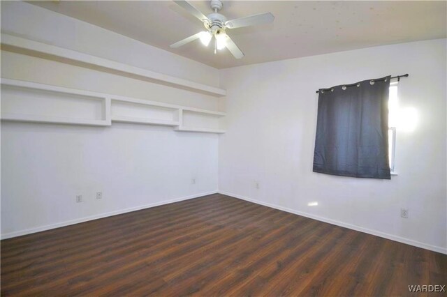 spare room featuring ceiling fan, dark wood-type flooring, and baseboards