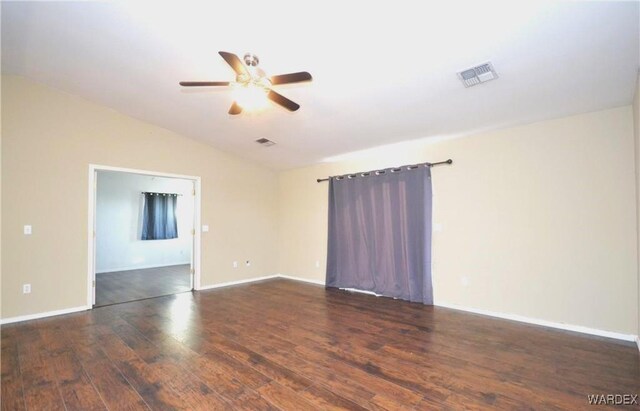 unfurnished room with dark wood-style flooring, visible vents, vaulted ceiling, and baseboards