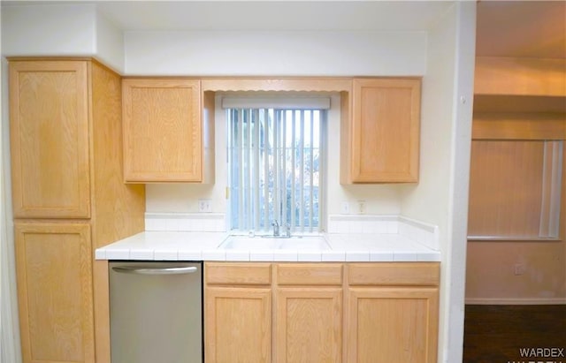 kitchen with light brown cabinetry, stainless steel dishwasher, and tile counters