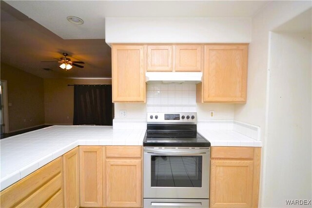 kitchen with tile countertops, electric range, light brown cabinets, and under cabinet range hood