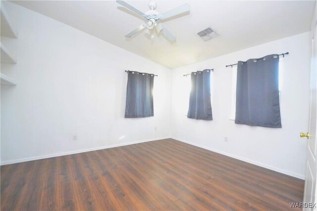 unfurnished room featuring visible vents, baseboards, lofted ceiling, dark wood-style floors, and ceiling fan