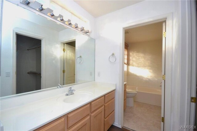 full bathroom with toilet, a tub, and vanity