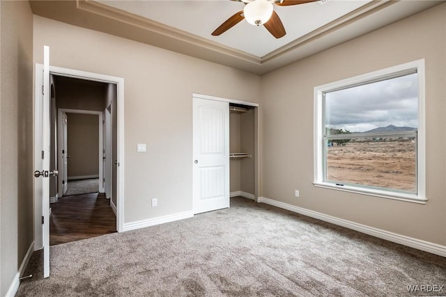 unfurnished bedroom with a ceiling fan, baseboards, dark colored carpet, and a closet