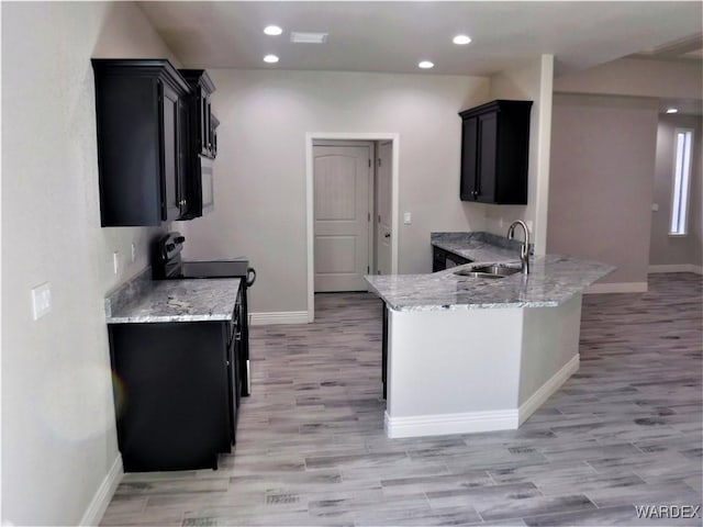 kitchen with a sink, light stone countertops, black / electric stove, and dark cabinetry