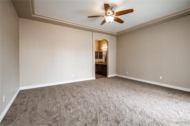 unfurnished room featuring arched walkways, ceiling fan, carpet flooring, and baseboards