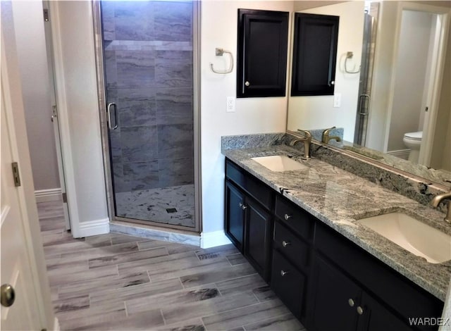 bathroom featuring double vanity, a sink, toilet, and wood tiled floor