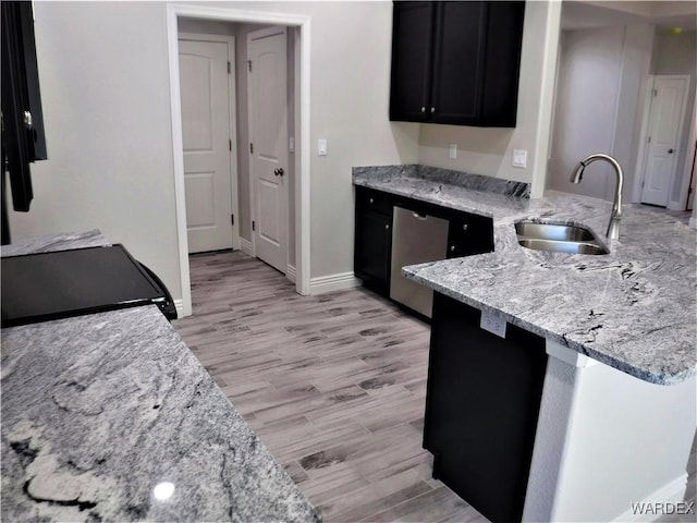 kitchen with electric range oven, a sink, light stone countertops, dark cabinetry, and dishwasher