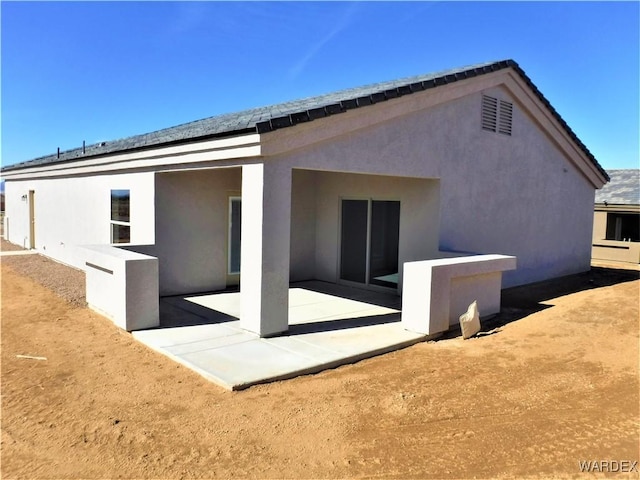 back of house featuring stucco siding and a patio