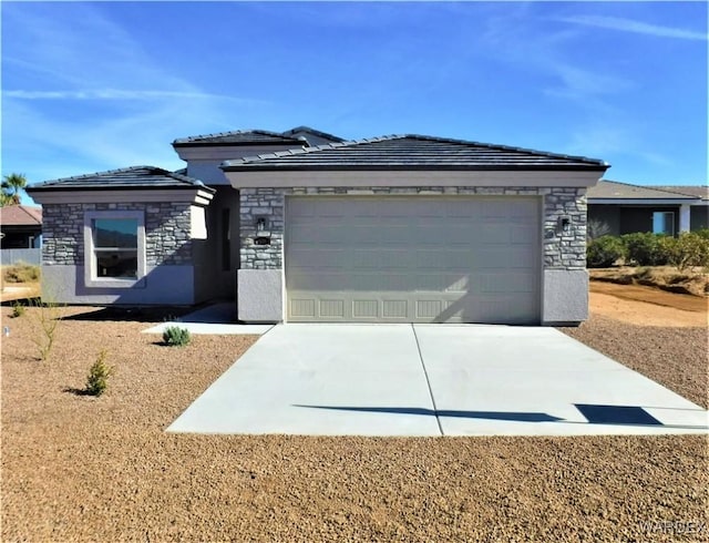 prairie-style house featuring an attached garage, stone siding, concrete driveway, and stucco siding