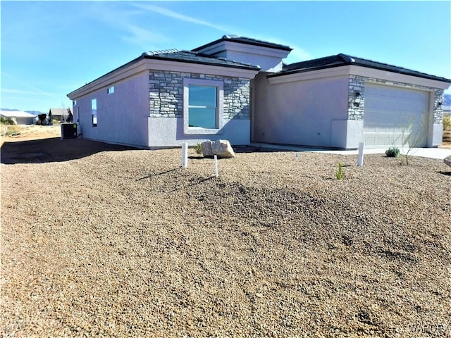 view of front of property featuring stone siding, central AC unit, an attached garage, and stucco siding