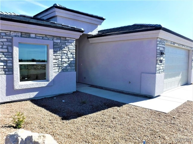 view of home's exterior with a garage, stone siding, and stucco siding